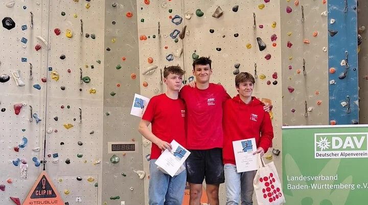 Drei Jungs bei der Siegerehrung vor einer Kletterwand | © Sebastian Heitzmann